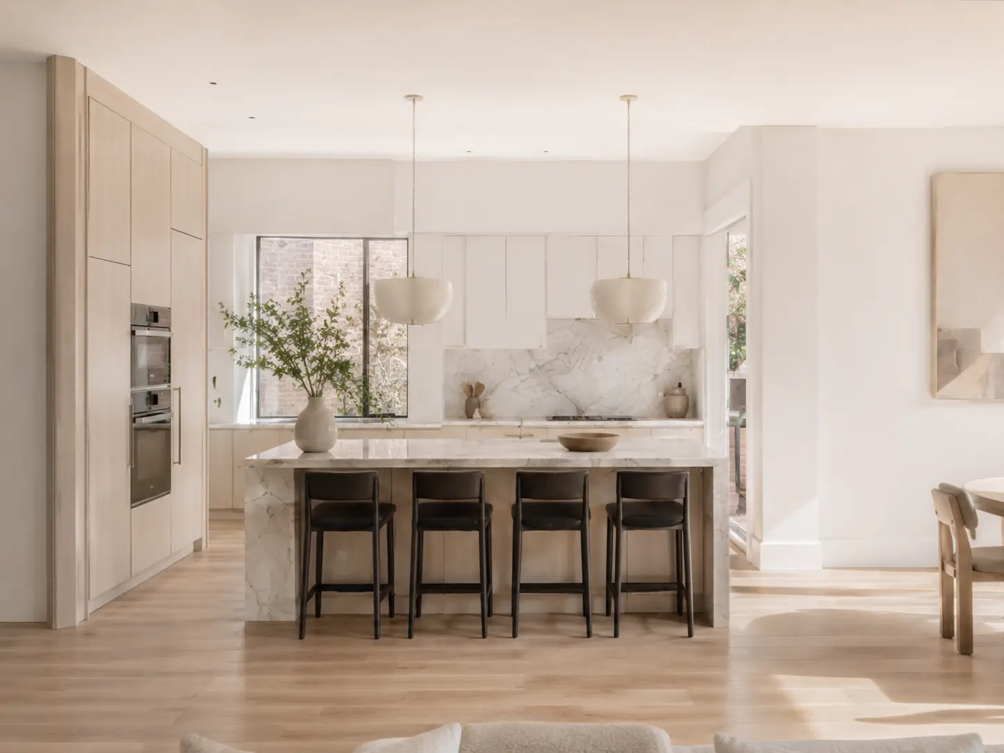 Cocina abierta y luminosa de una vivienda reformada en Madrid con isla de mármol y suelo de madera