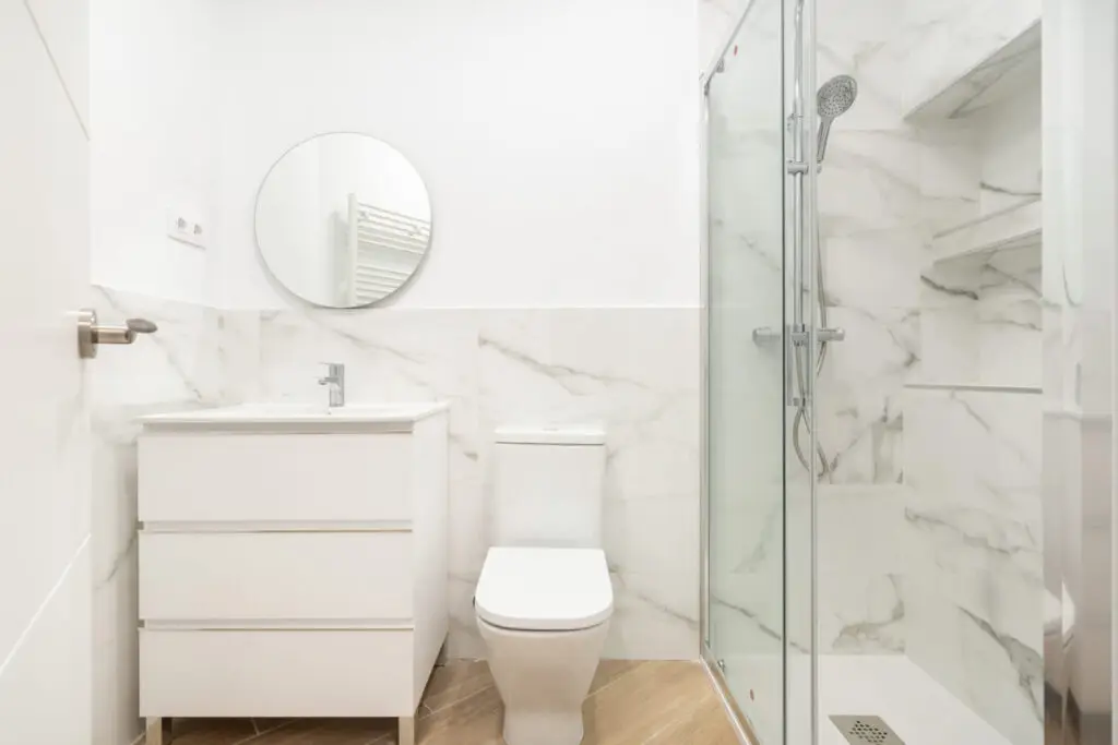 Baño reformado con plato de ducha y azulejo de mármol en una vivienda de Tetuán, Madrid