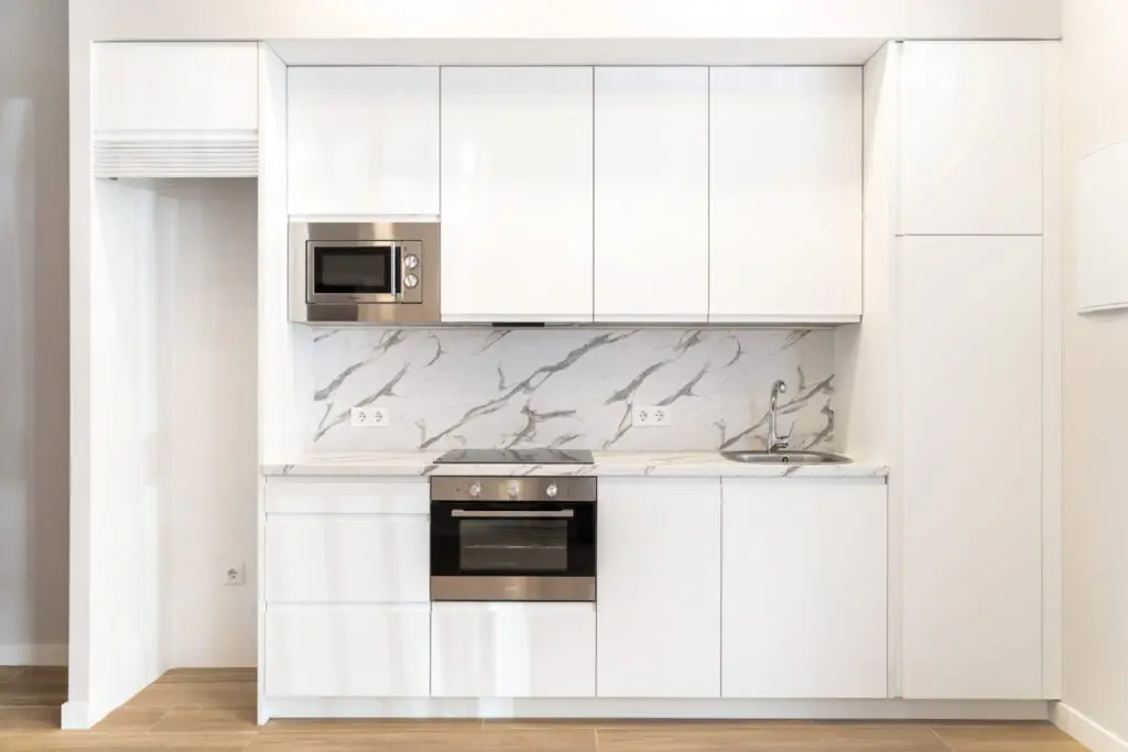 Cocina blanca con frente de mármol en una vivienda tras un cambio de uso en Tetuán, Madrid