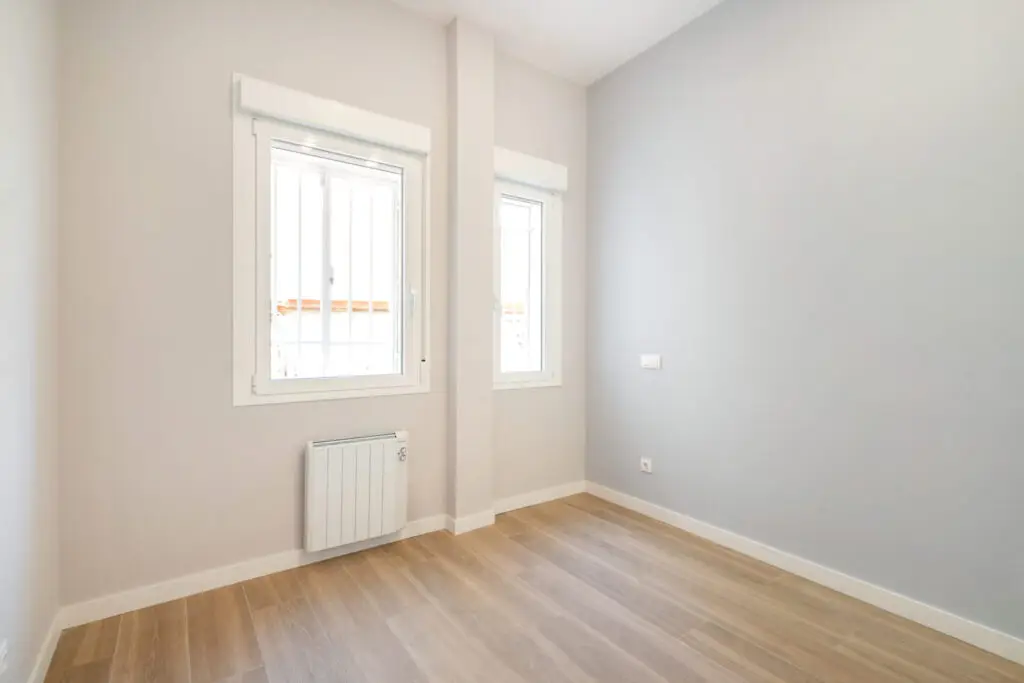Dormitorio luminoso con dos ventanas en una vivienda tras cambio de uso en Tetuán, Madrid