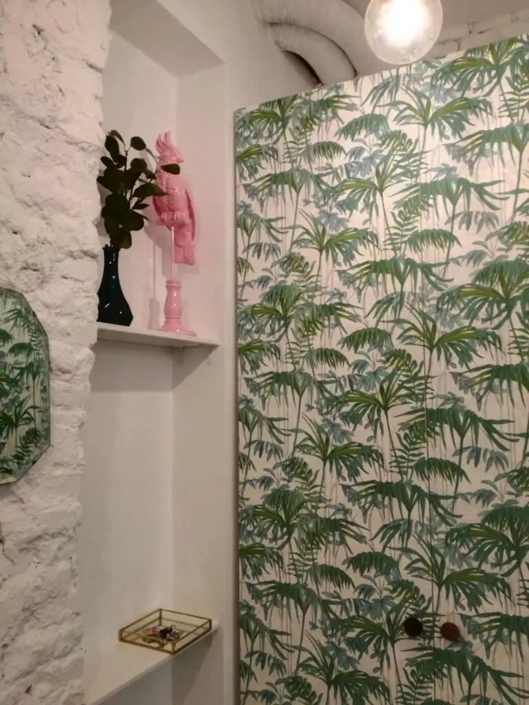Rincón con papel pintado tropical y hornacina en piedra blanca en una vivienda reformada en Lavapiés, Madrid