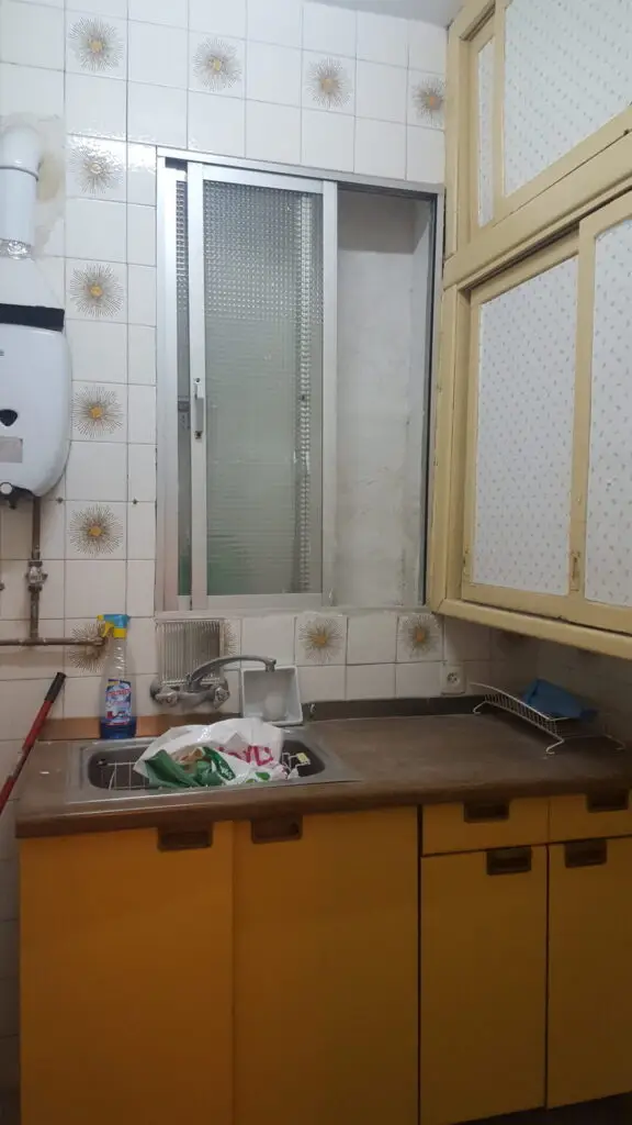 Cocina antigua con muebles amarillos y azulejo desgastado en Lavapiés, antes de la reforma
