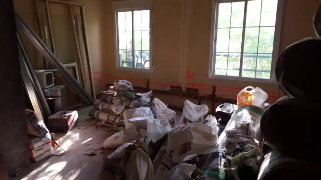 Estancia del piso durante la obra de reforma, con sacos de material y las instalaciones marcadas