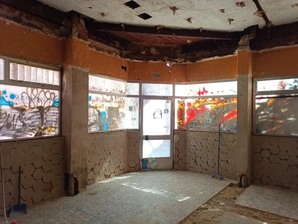 Local vacío y deteriorado, con escombros en el suelo y grafitis en los escaparates