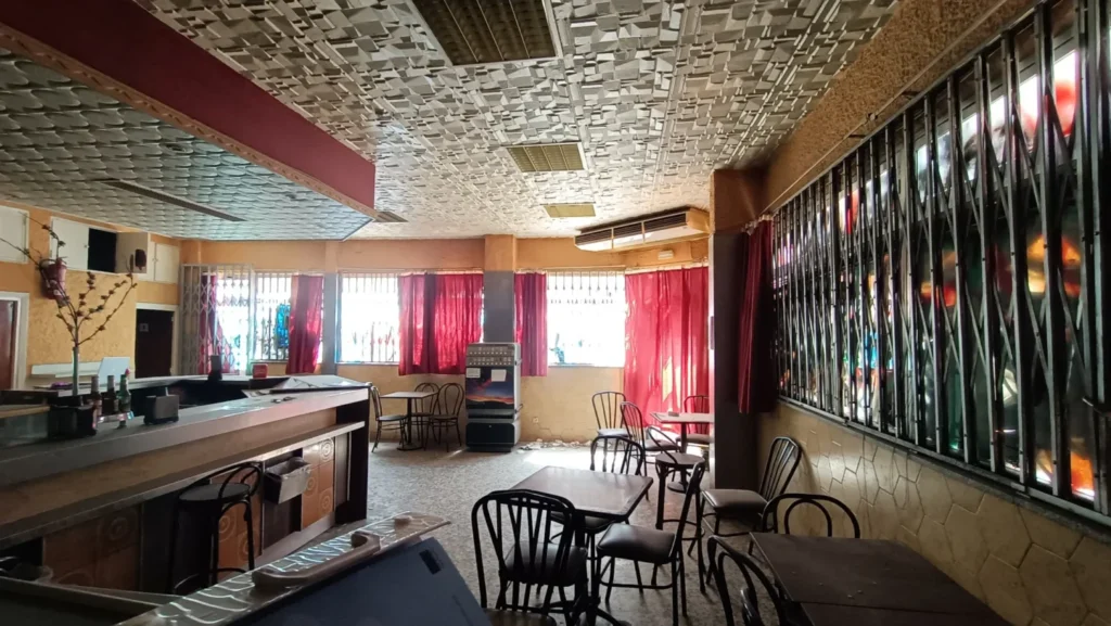Interior de la antigua marisquería con la barra, mesas, cortinas rojas y techo de placas decorativas