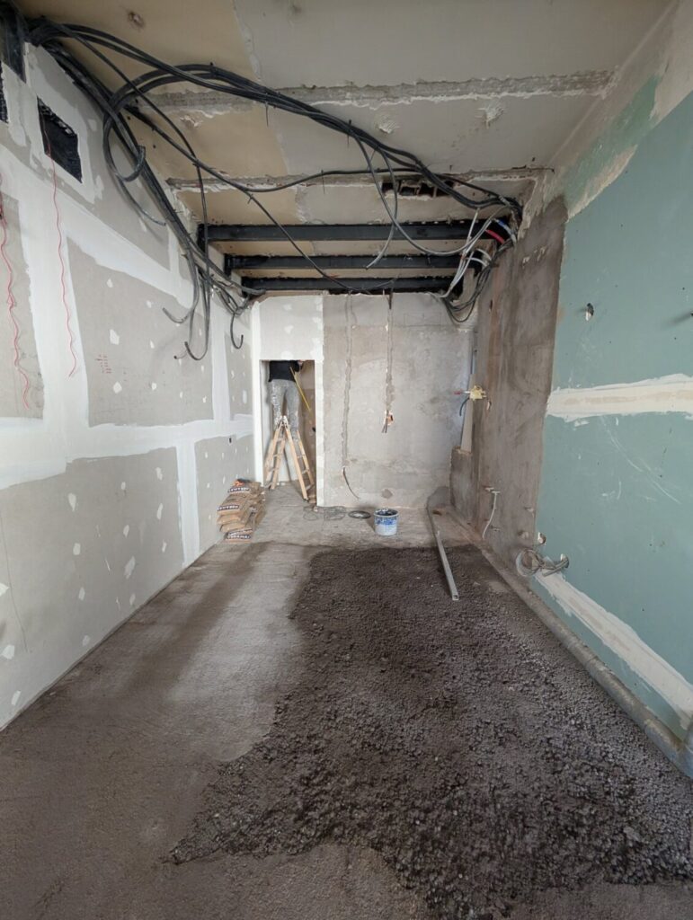 Pasillo de un piso en obra en Comillas, Carabanchel, con el techo abierto y los tabiques retirados