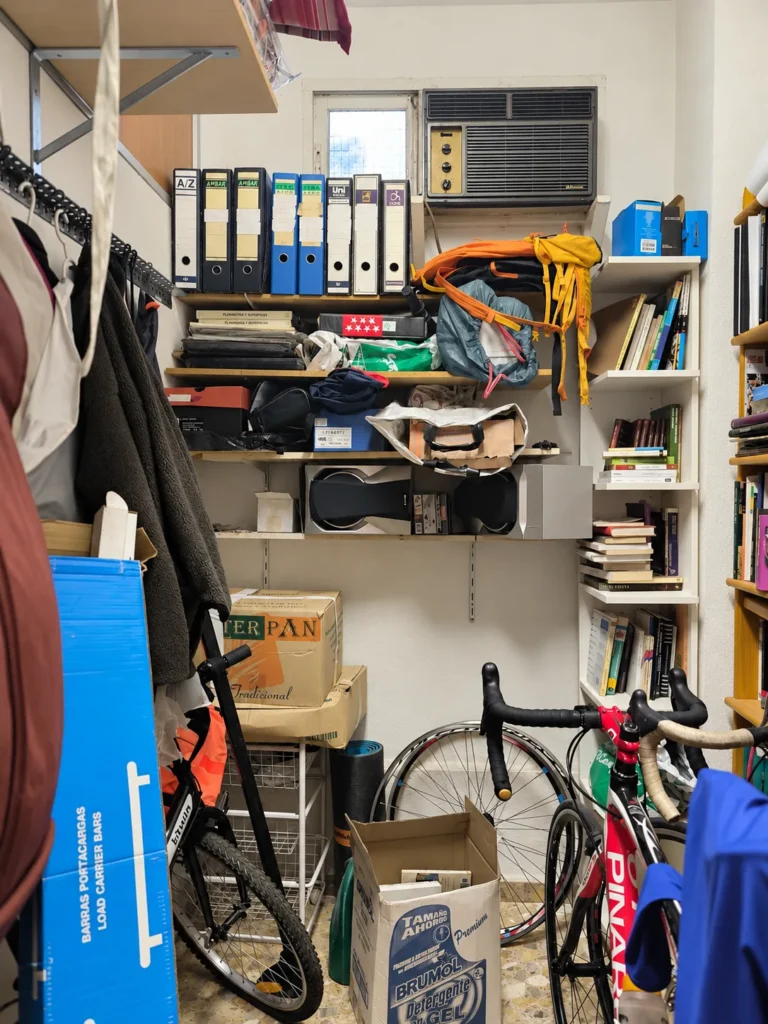 Local usado como almacén, lleno de estanterías, cajas, bicicletas y objetos acumulados